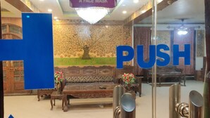A hotel lobby with a 'PUSH' sign, a 'PLEASE WEAR A FACE MASK' sign, and a 'PUSH' button. - Hotel Centre Point (Srinagar)