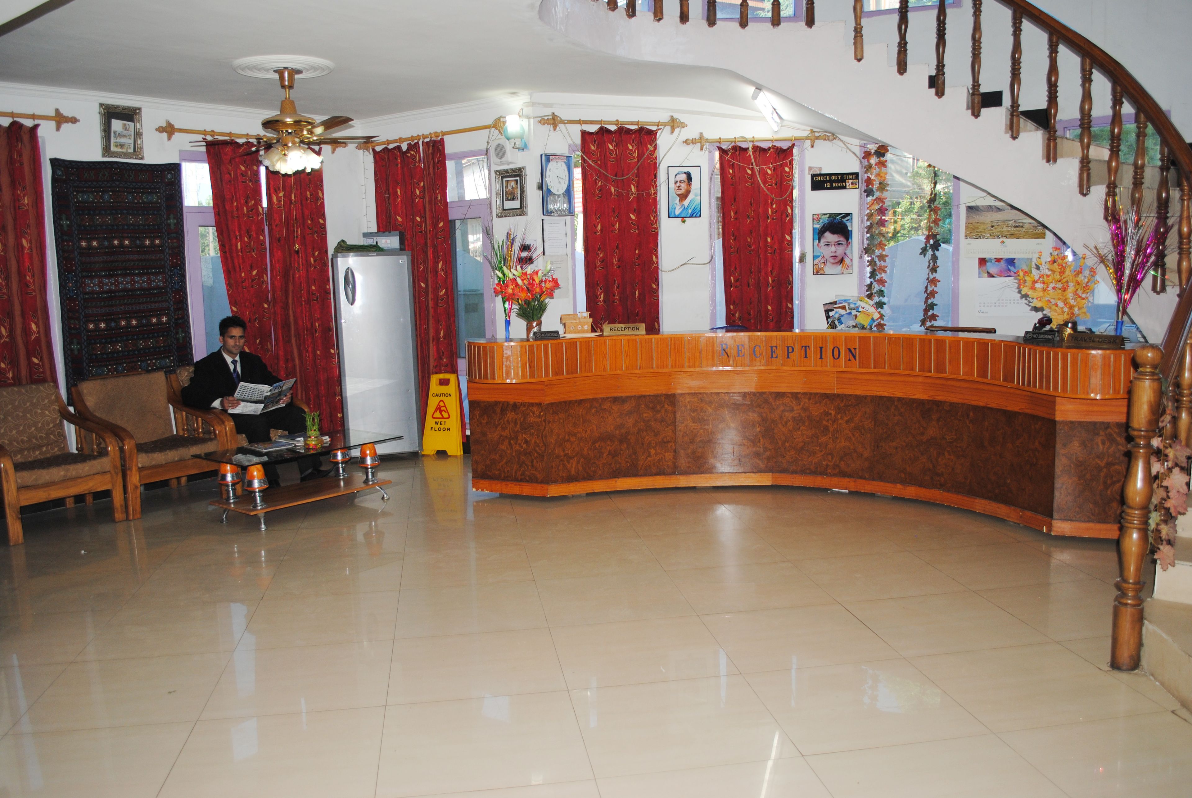 A reception area with a curved wooden desk, a ceiling fan, and a staircase.