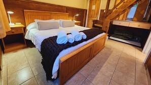 A bedroom with a large bed, wooden headboard, and a fireplace. - Hotel del Glaciar Libertador (El Calafate)