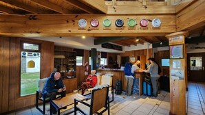 A wooden interior with a reception desk, seating area, and clocks on the wall. - Hotel del Glaciar Libertador (El Calafate)