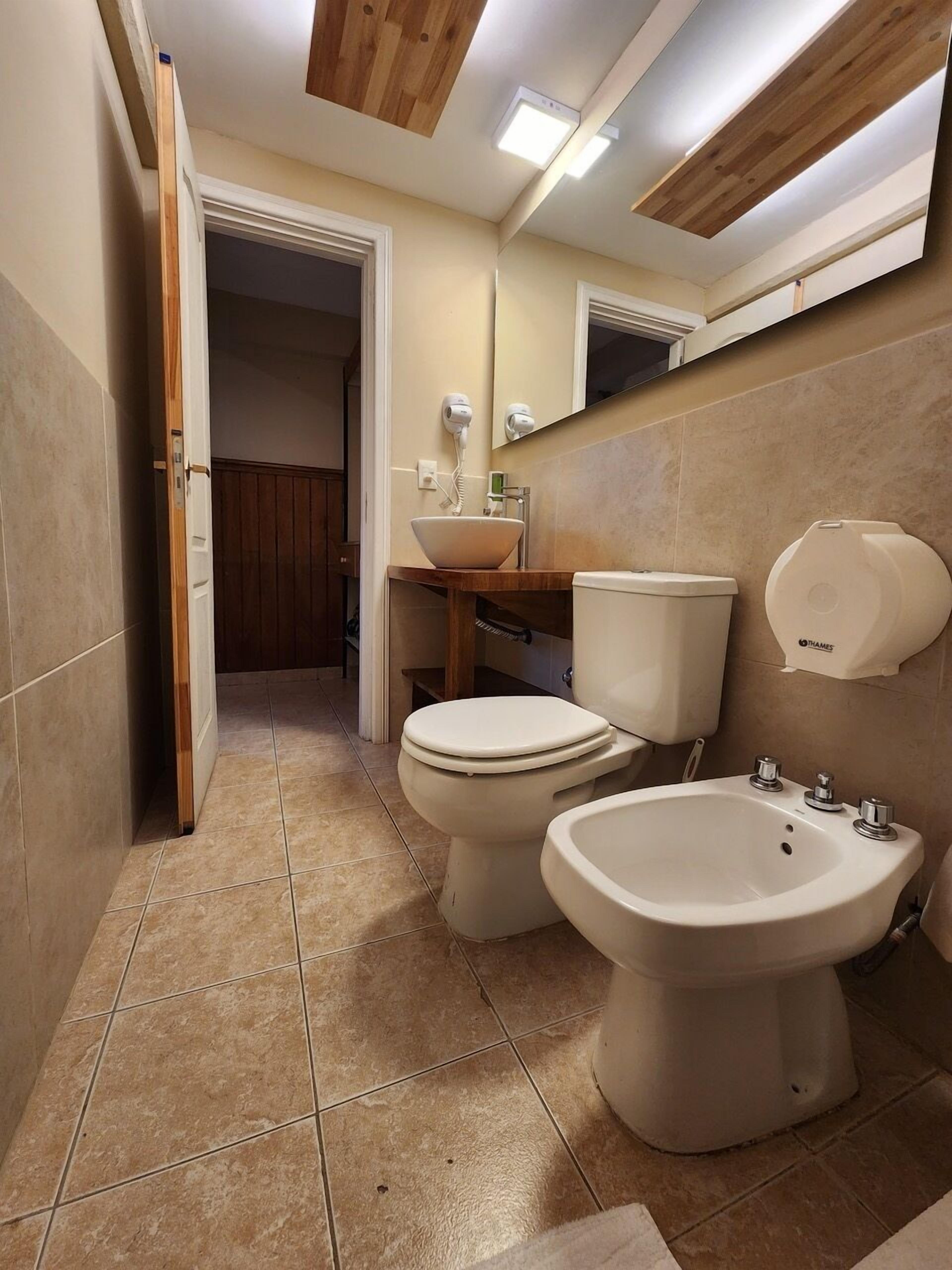 A bathroom with a toilet, bidet, sink, and mirror.