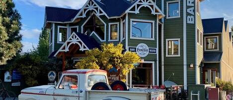 A vintage white truck parked in front of a green building with a sign reading "BAR PIONEROS RESTO".