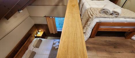 Un dormitorio estilo loft acogedor, con techo de madera, una cama grande con ropa blanca y una mesita de noche con lámpara.