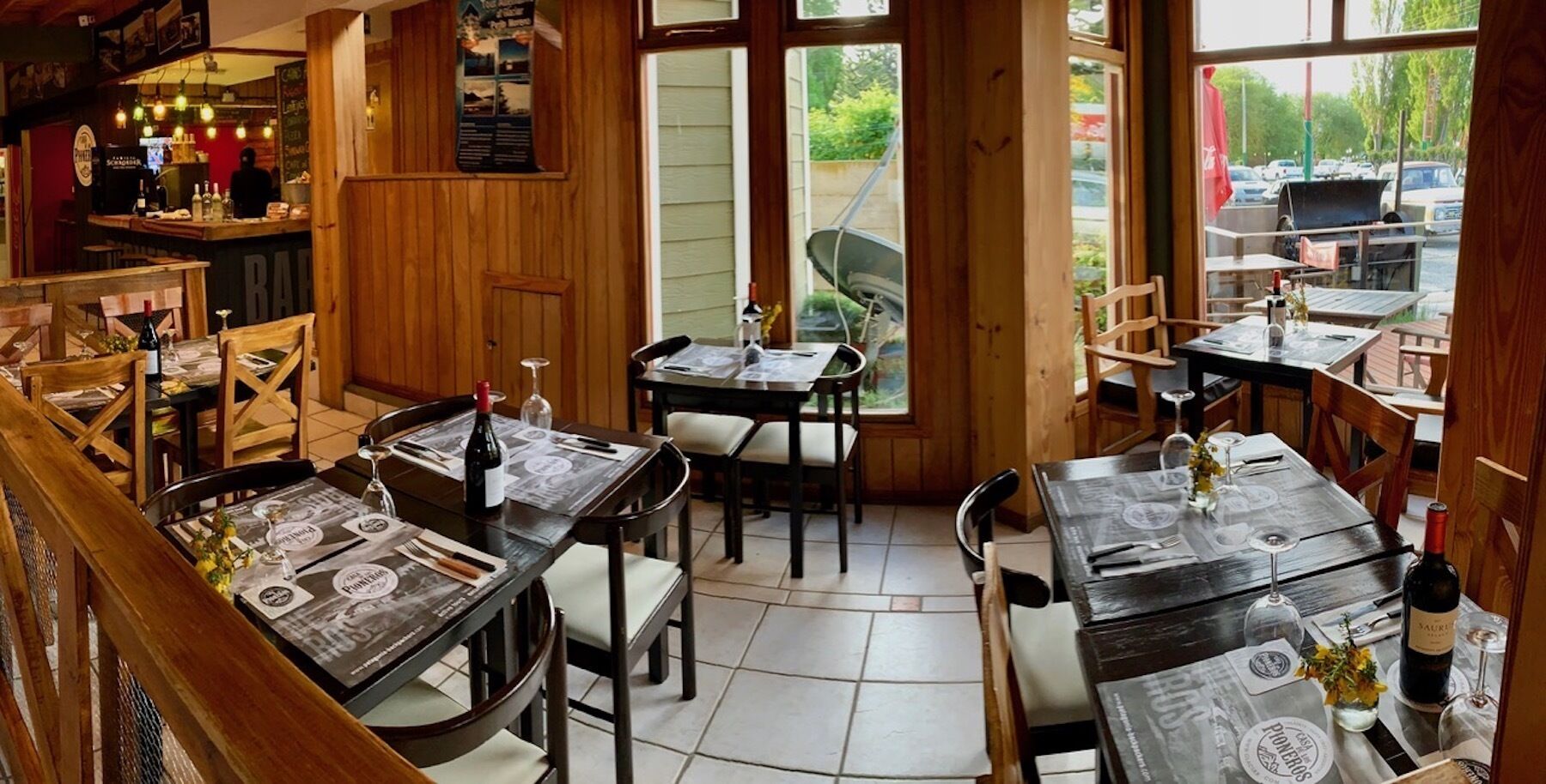 Un restaurante con interiores de madera, varias mesas y sillas.