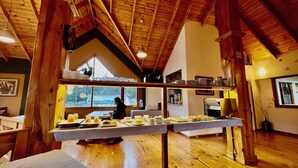 A rustic dining area with wooden beams, a high ceiling, and a view of the outdoors. - Hotel del Glaciar Libertador (El Calafate)