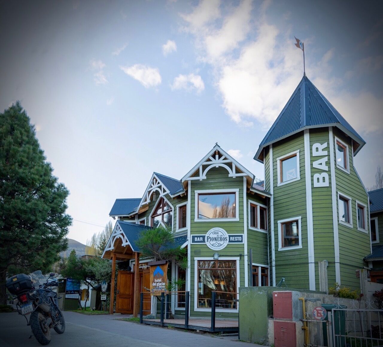 A green building with a bar and a restaurant sign.
