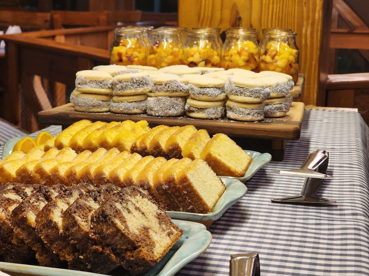 Une table de buffet avec divers desserts et un bocal de fruits.