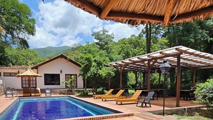 A pool area with wooden loungers and a thatched roof structure. - Hotel Selva Montana (Villa San Lorenzo)