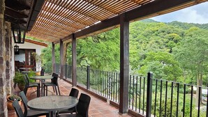 An outdoor patio with a wooden pergola, terracotta tiles, and a view of lush greenery. - Hotel Selva Montana (Villa San Lorenzo)