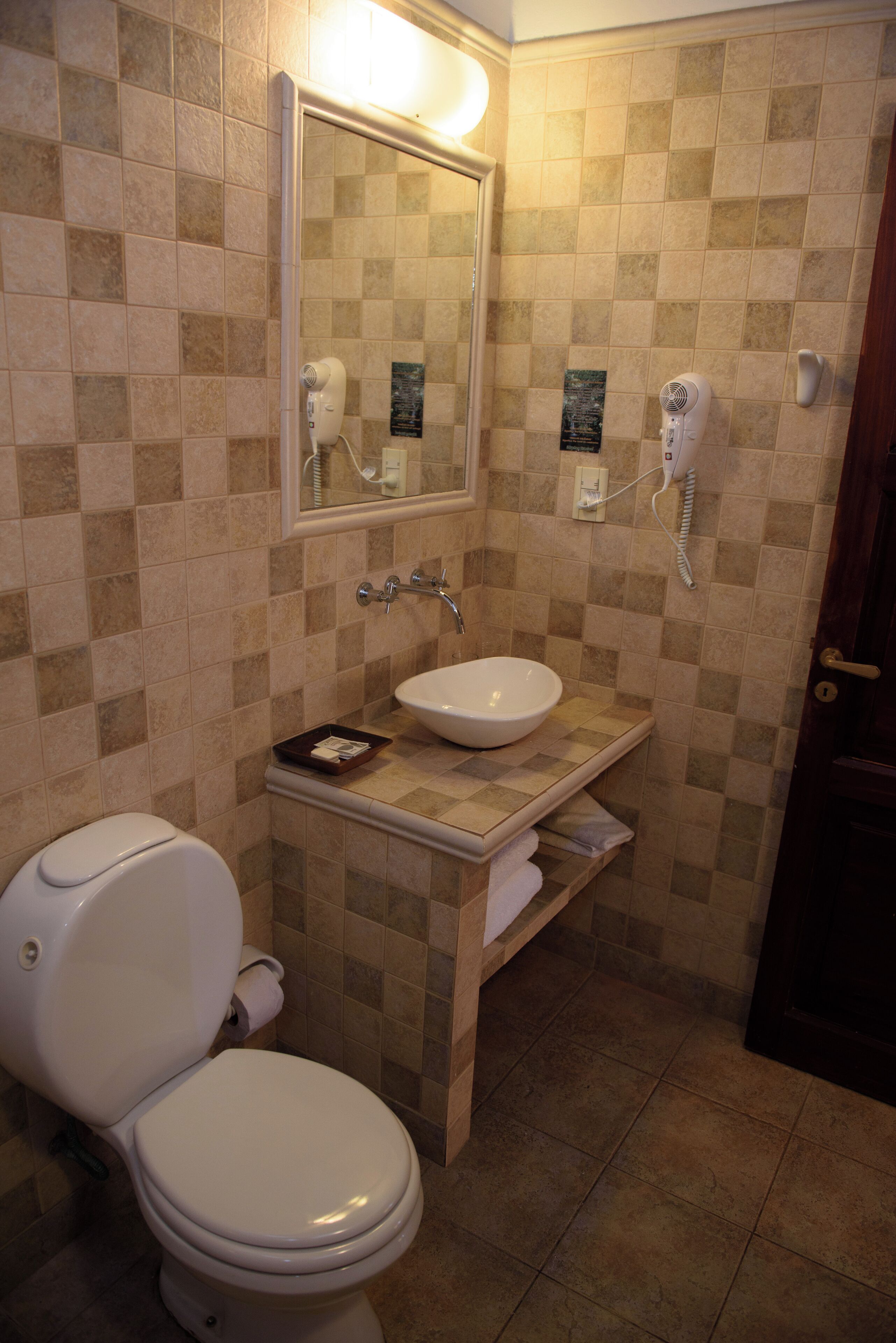 Un baño con inodoro, lavamanos y espejo.