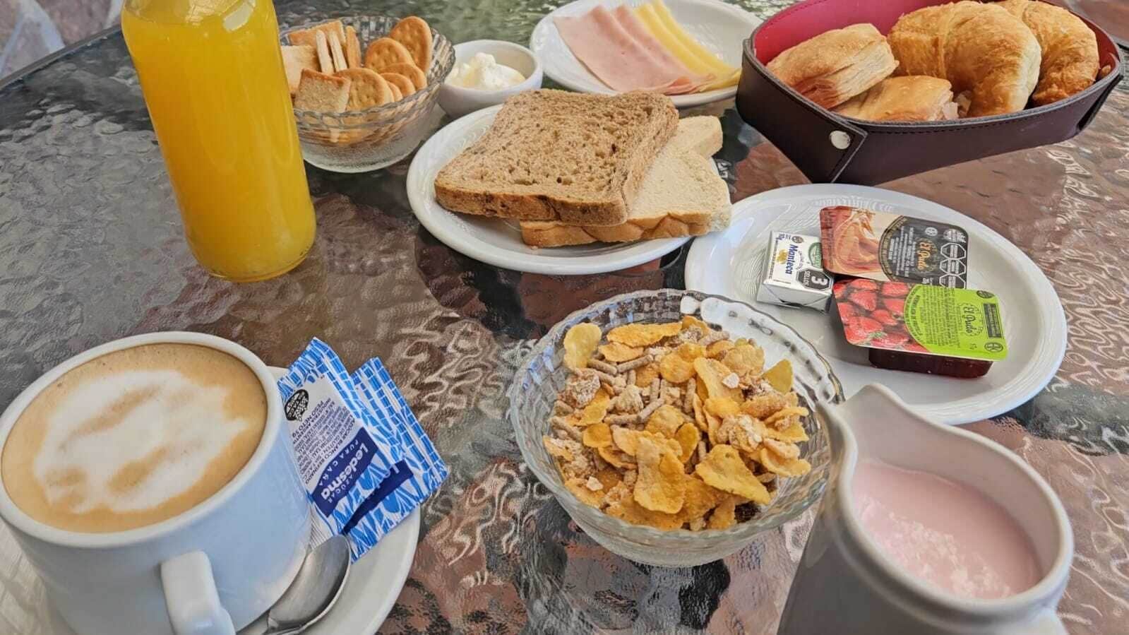 Une table de petit-déjeuner avec divers aliments, notamment des tartines, des céréales et une tasse de café.