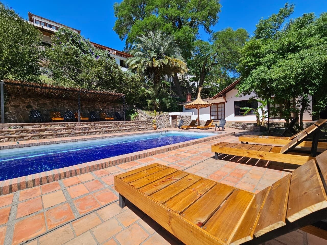 A swimming pool with wooden loungers and a stone wall.