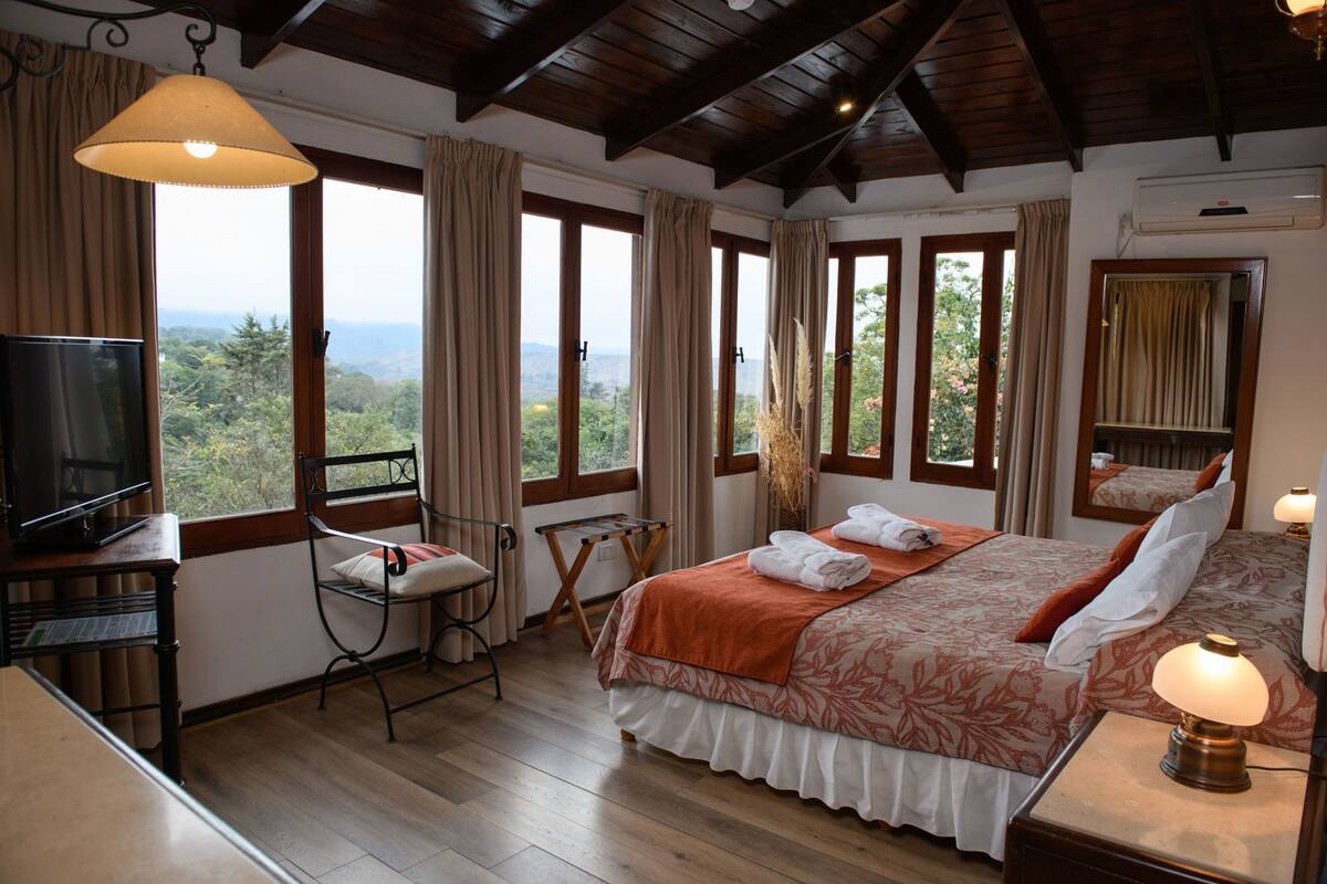 A bedroom with a bed, a TV, a desk, and a chair.