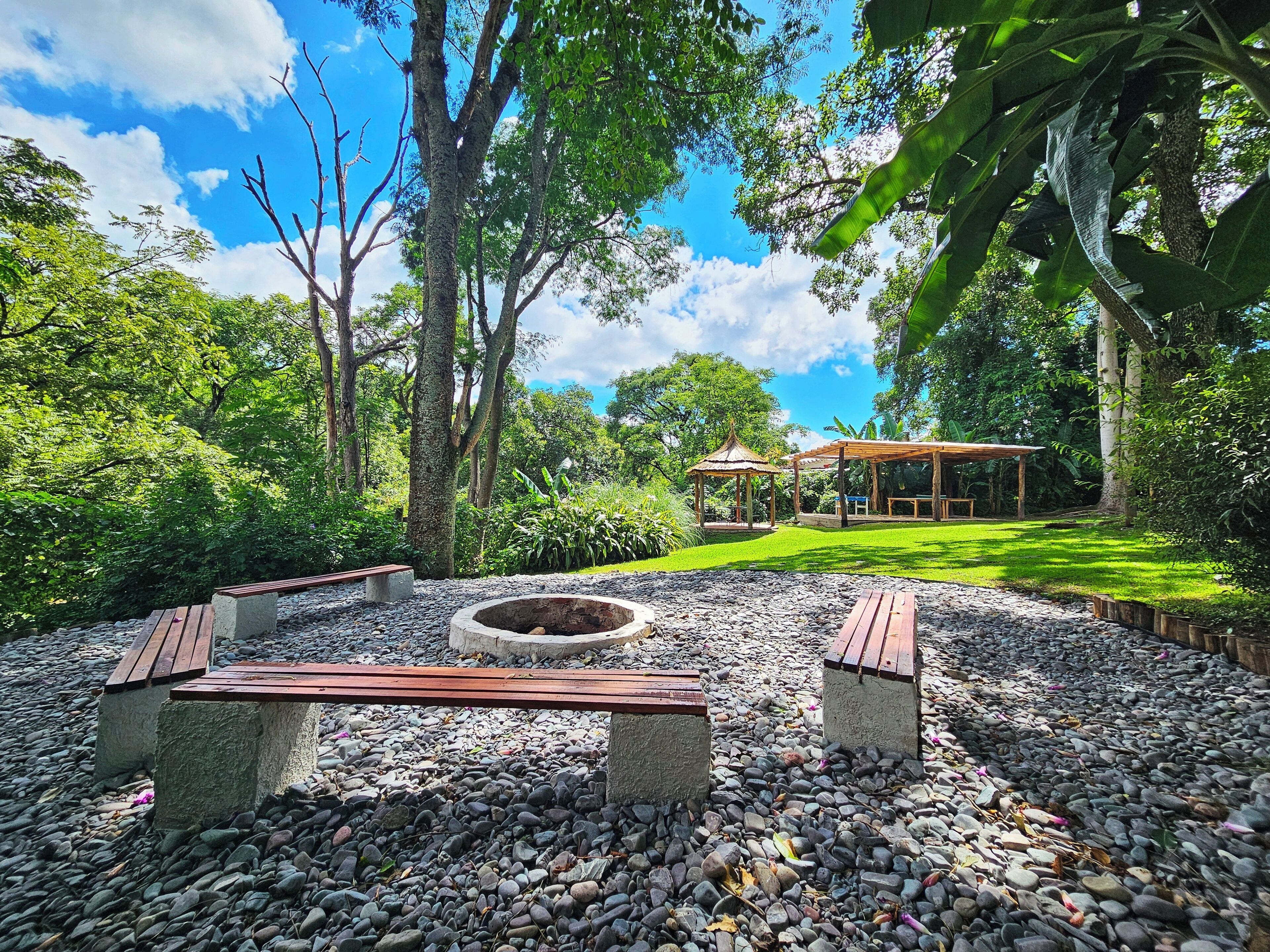 A garden with a gazebo, a fire pit, and a wooden bench.