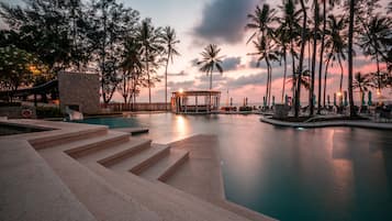 A swimming pool with steps leading into it, surrounded by palm trees and a gazebo.