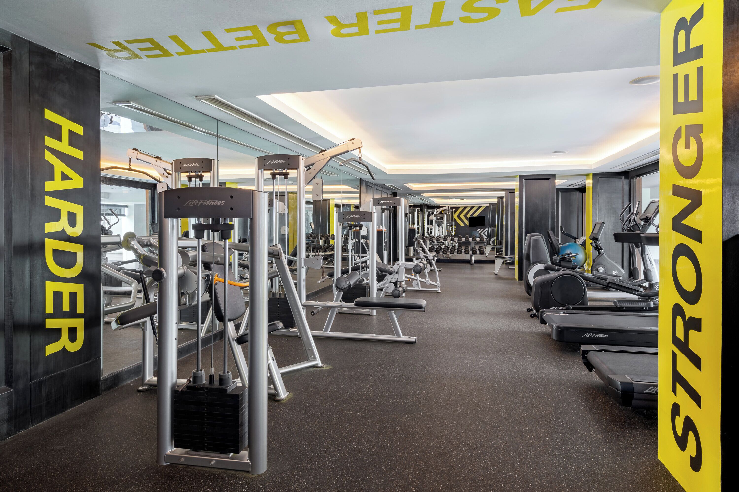 Un gimnasio con equipo de ejercicio, espejos y pancartas motivacionales.