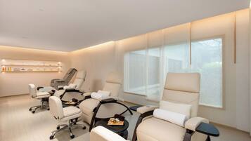 Um spa moderno com várias cadeiras de massagem, um balcão de atendimento e uma prateleira na parede com produtos.