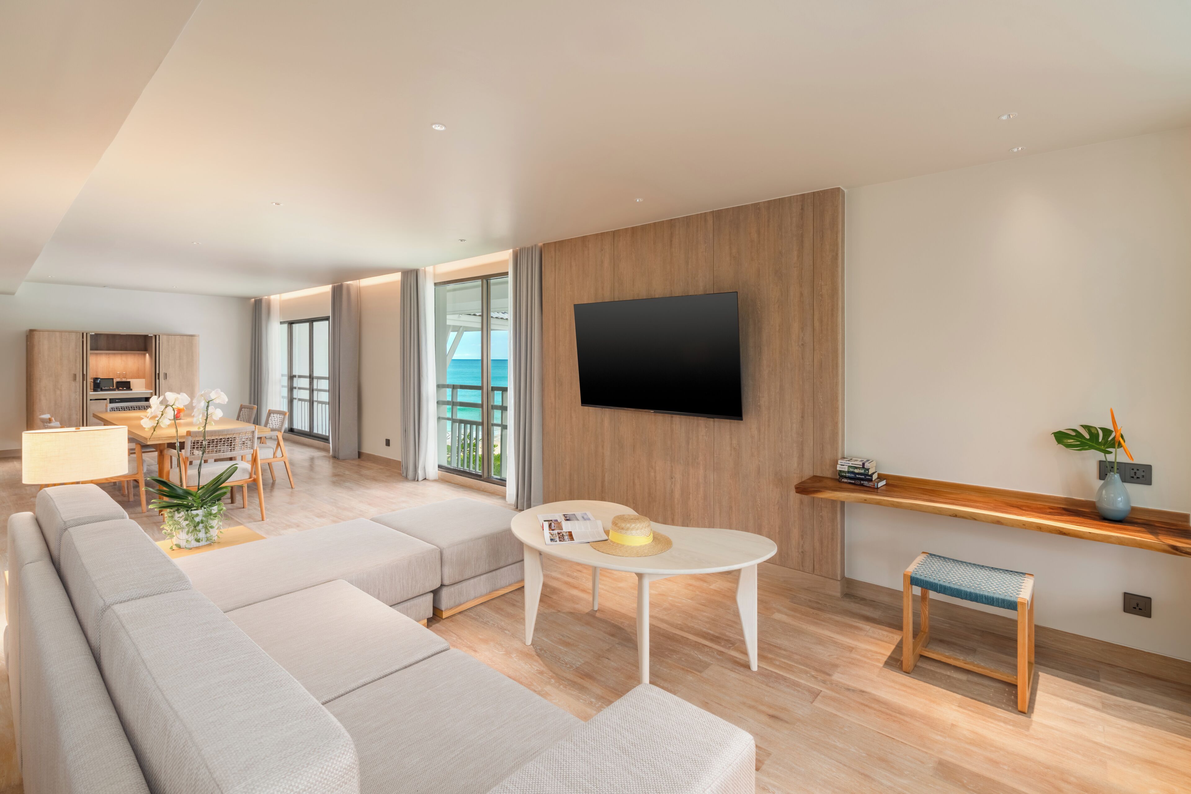 Un salon moderne avec un canapé, une table à manger et un téléviseur fixé au mur.