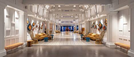 A spacious hotel lobby with high ceilings, modern furniture, and decorative wall art.
