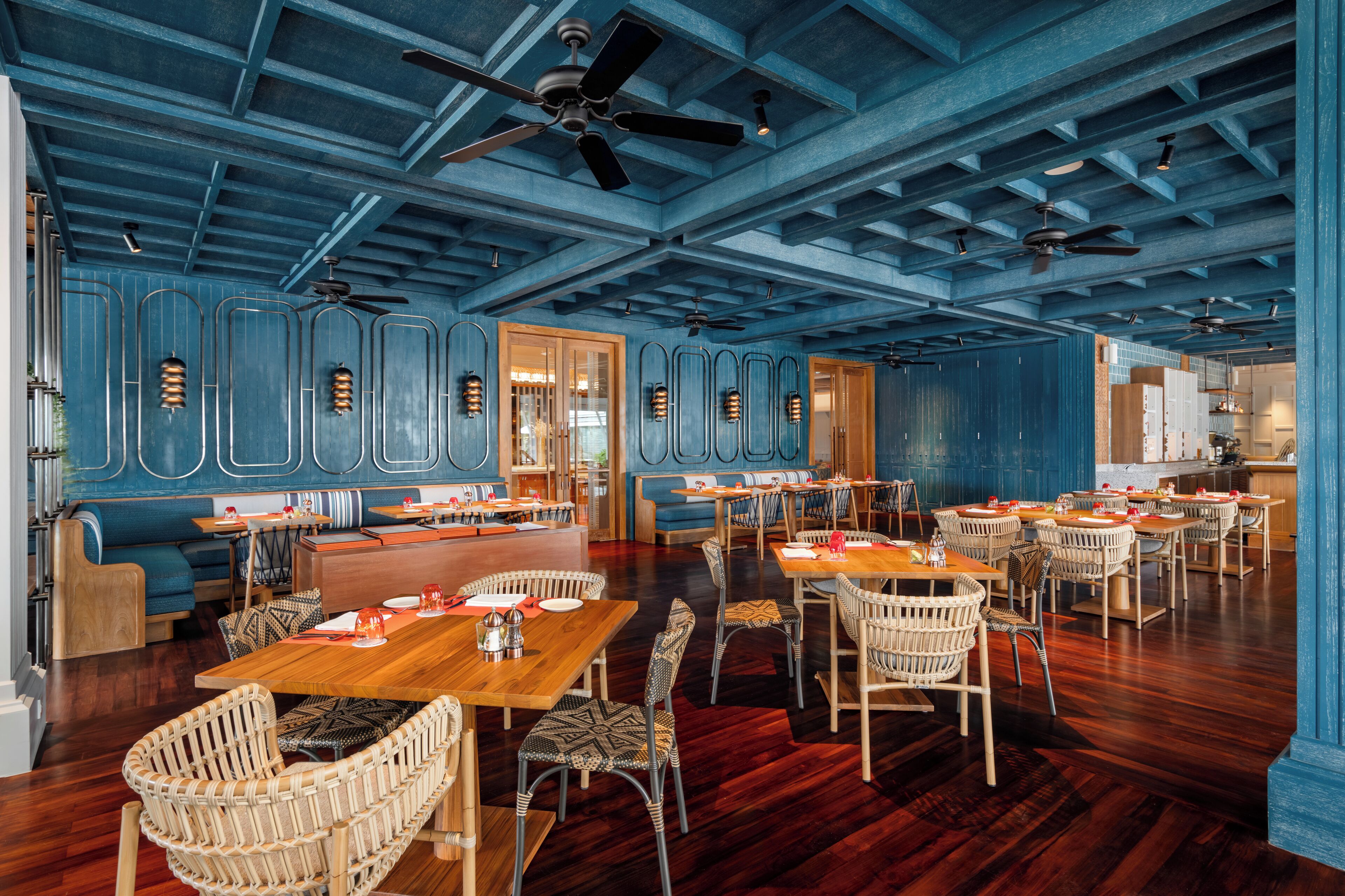 A spacious restaurant with high ceilings, wooden flooring, and multiple seating areas including tables and booths.