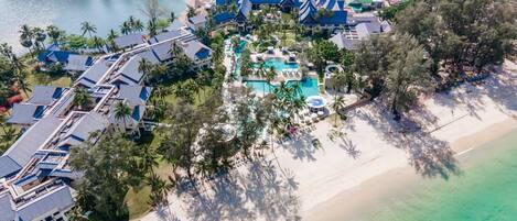 An aerial view of a resort with multiple buildings, a large pool area, and a beach.