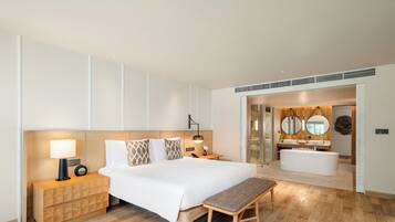 Una habitación de hotel moderna con una cama grande, mesitas de noche, un banco, un baño con bañera y un espejo.