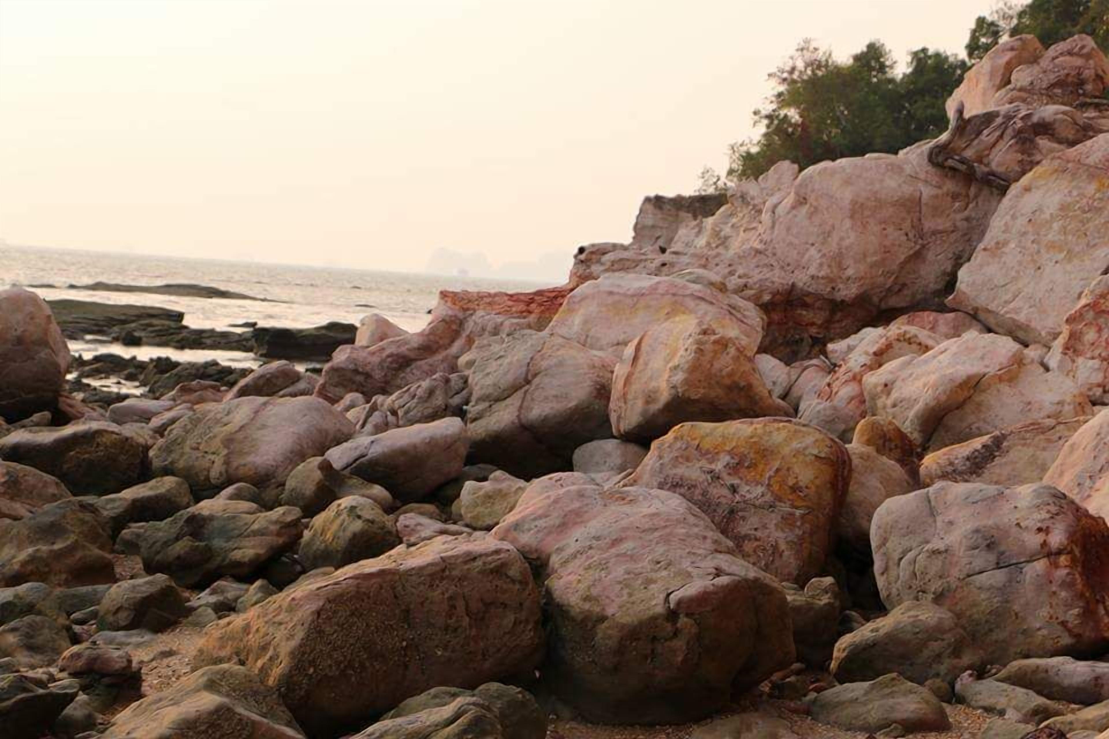 Una costa rocciosa con massi grandi e vista sull'oceano sullo sfondo.