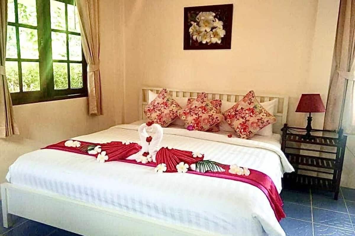 A neatly made bed with a floral arrangement and a heart-shaped towel.