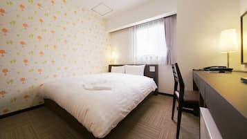 A hotel room with a bed, a desk, a chair, and a window with curtains.