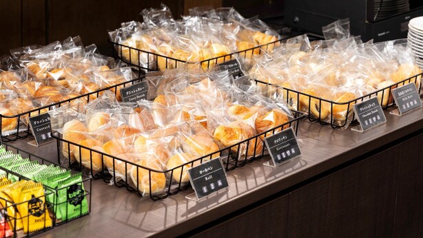 Une vitrine de boulangerie présentant diverses pâtisseries emballées dans des sachets en plastique transparent, avec des étiquettes indiquant des noms tels que « chaussons aux épices » et « chaussons au chocolat ».