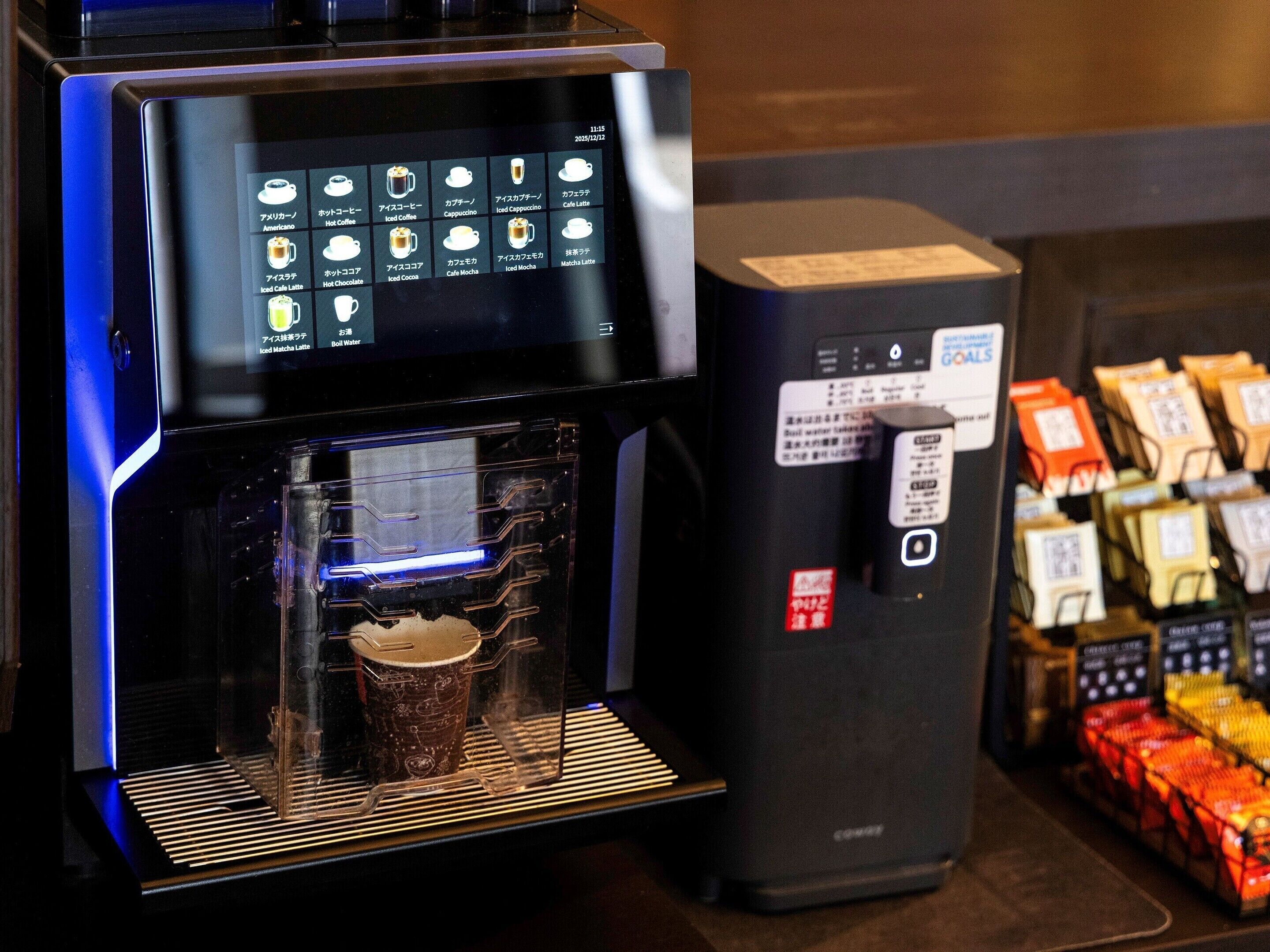 Une machine à café dotée d’un écran numérique, d’une tasse à café et d’un compartiment pour ranger les dosettes de café.