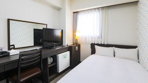 Une chambre d’hôtel comprenant un lit, un bureau avec une télévision, un petit réfrigérateur, une chaise et une fenêtre avec des rideaux.