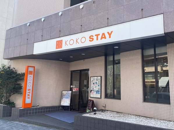 Un edificio con un cartel que dice 'KOKO STAY' y un área de descanso con un letrero.
