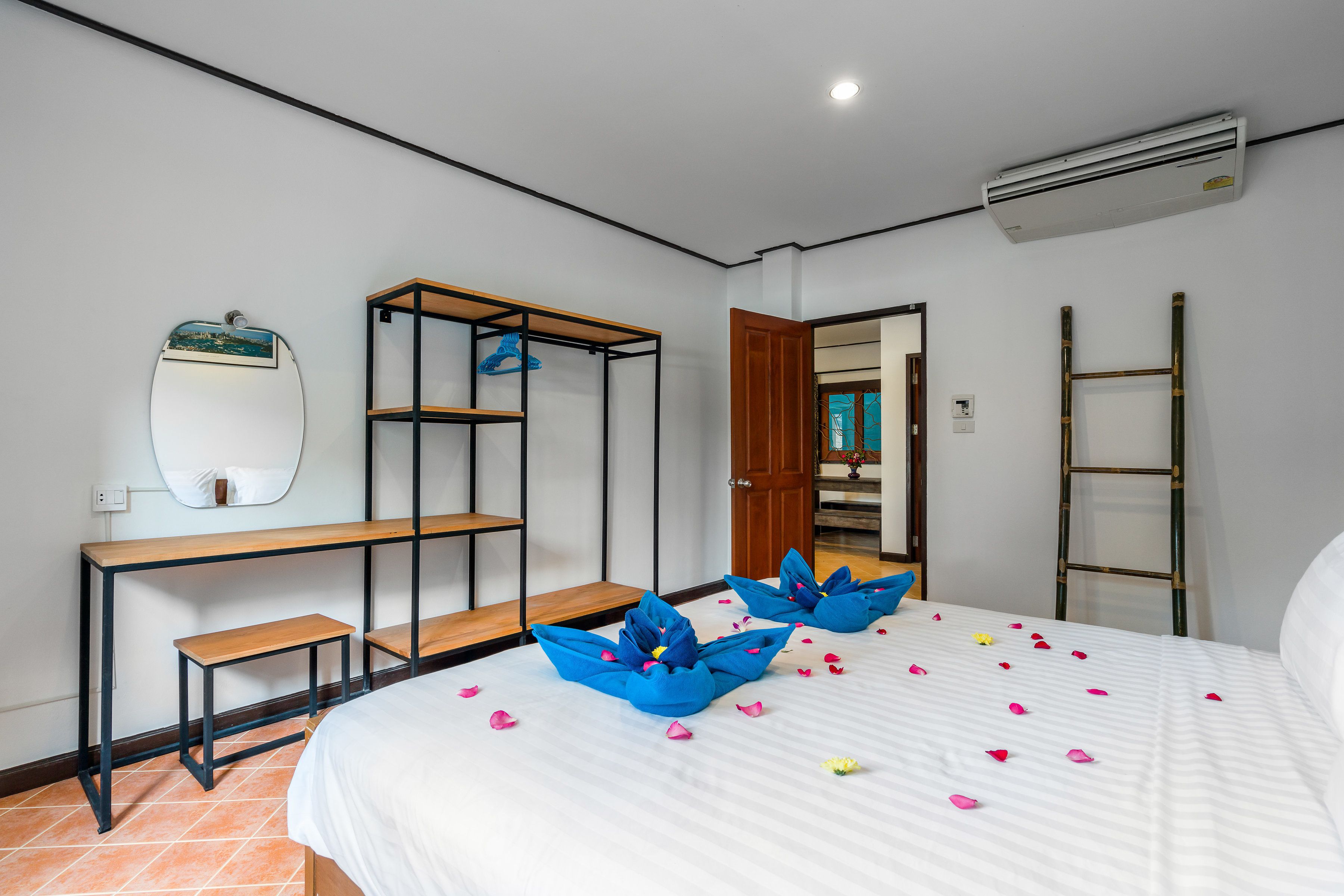 A bedroom with a bed, a wooden bench, a metal shelf unit, and a ladder.