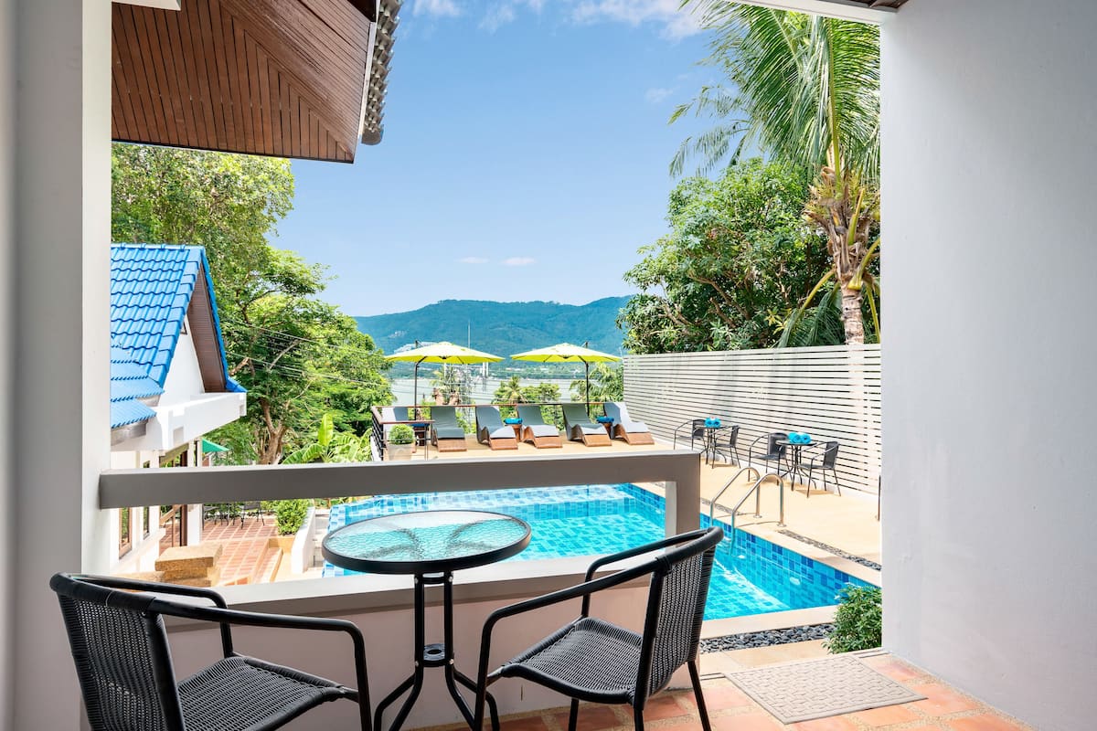 A balcony with a pool, two chairs, and a table.