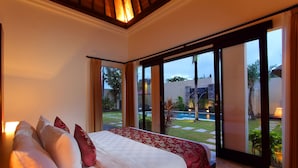 Un dormitorio con una cama grande, vistas a un jardín y una puerta corrediza de vidrio que da a un espacio exterior.