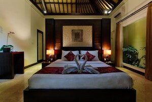 A hotel room with a large bed, two bedside lamps, a decorative wall piece, and a large window with curtains.