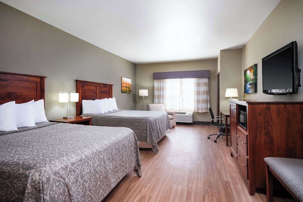 Una habitación de hotel con dos camas, un escritorio, televisión y una silla.