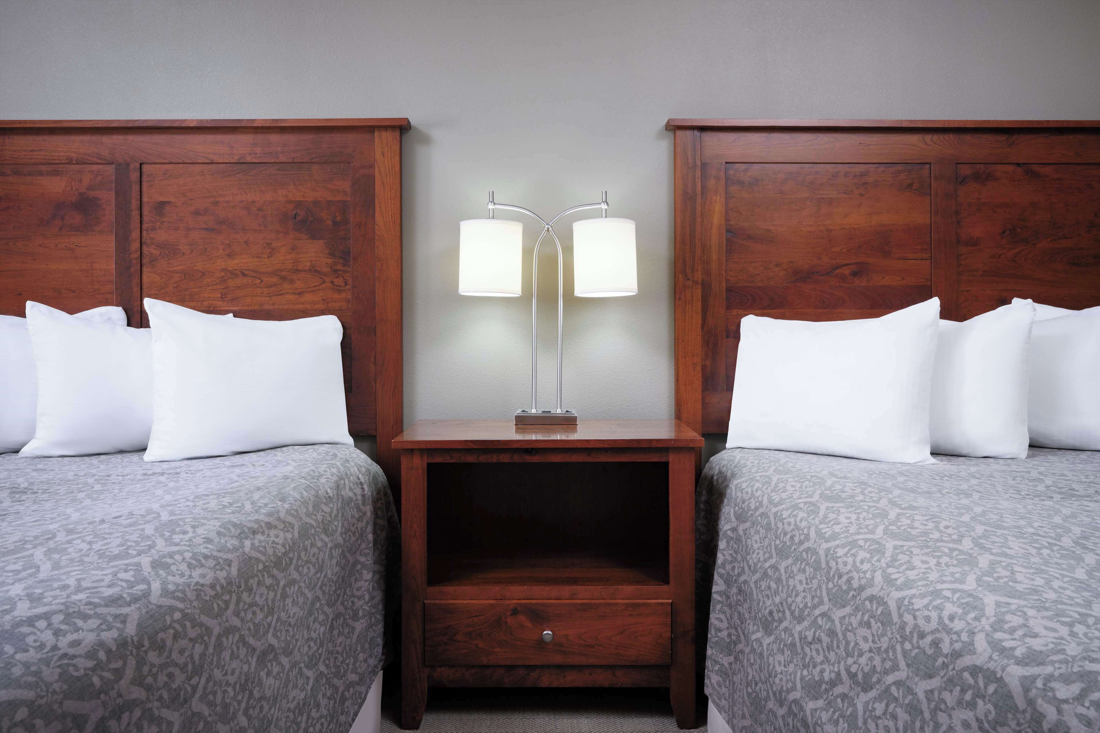 A double room with two beds, a nightstand between them, and a floor lamp.