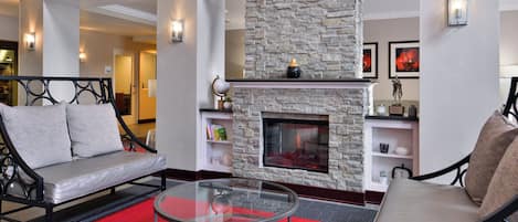 A modern living room with a stone fireplace, a glass coffee table, and two sofas.