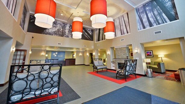 A spacious lobby with modern furniture, a fireplace, and large windows with forest views.