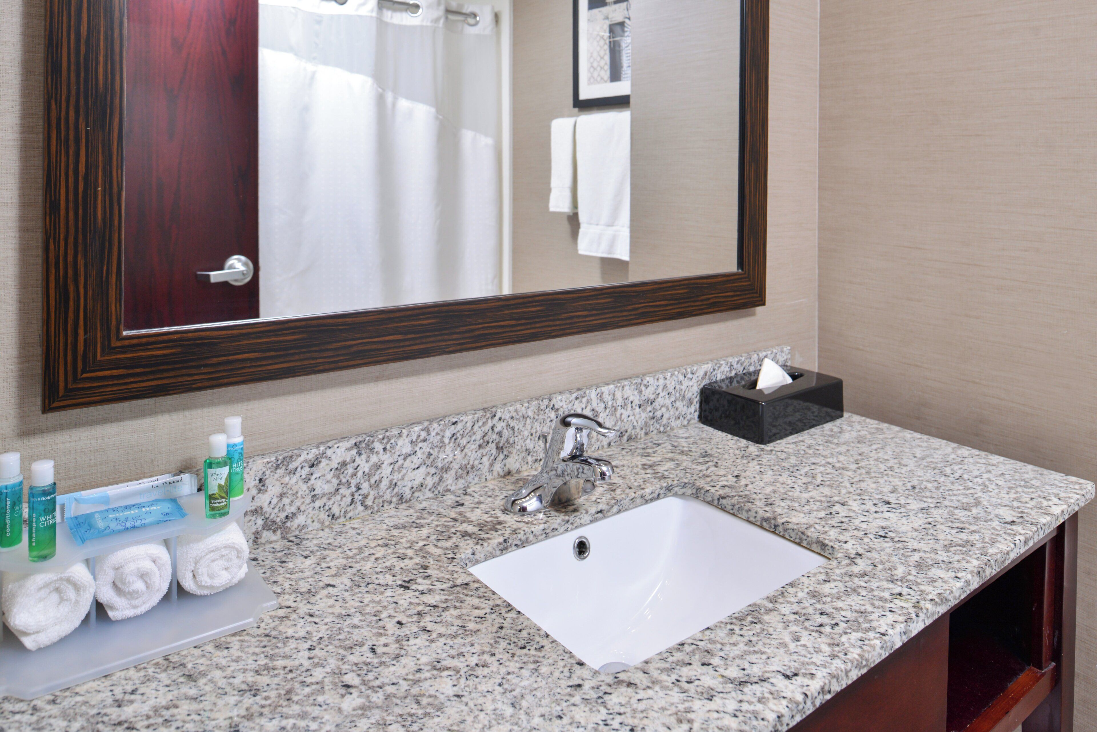 A bathroom with a marble sink, a mirror, and toiletries.