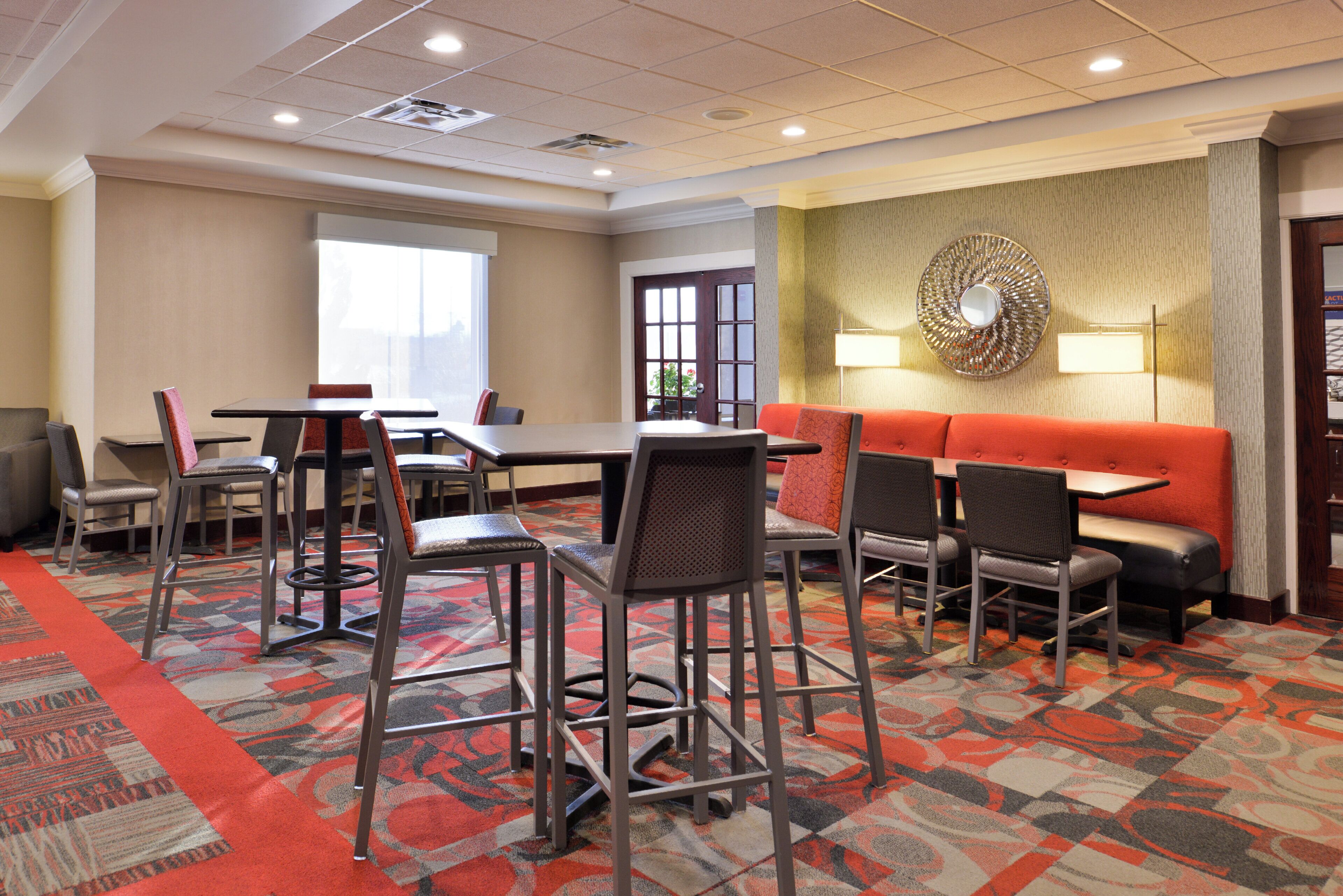 A hotel conference room with a long table, multiple chairs, a sofa, and a patterned carpet.
