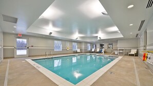 An indoor swimming pool with clear water, tiled floor, and a ceiling with recessed lighting.