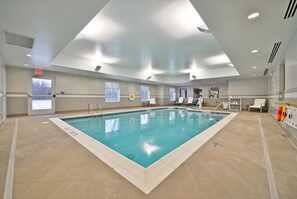 Ein Innenpool mit klarem Wasser, gefliestem Boden und einer Decke mit Einbaustrahlern.