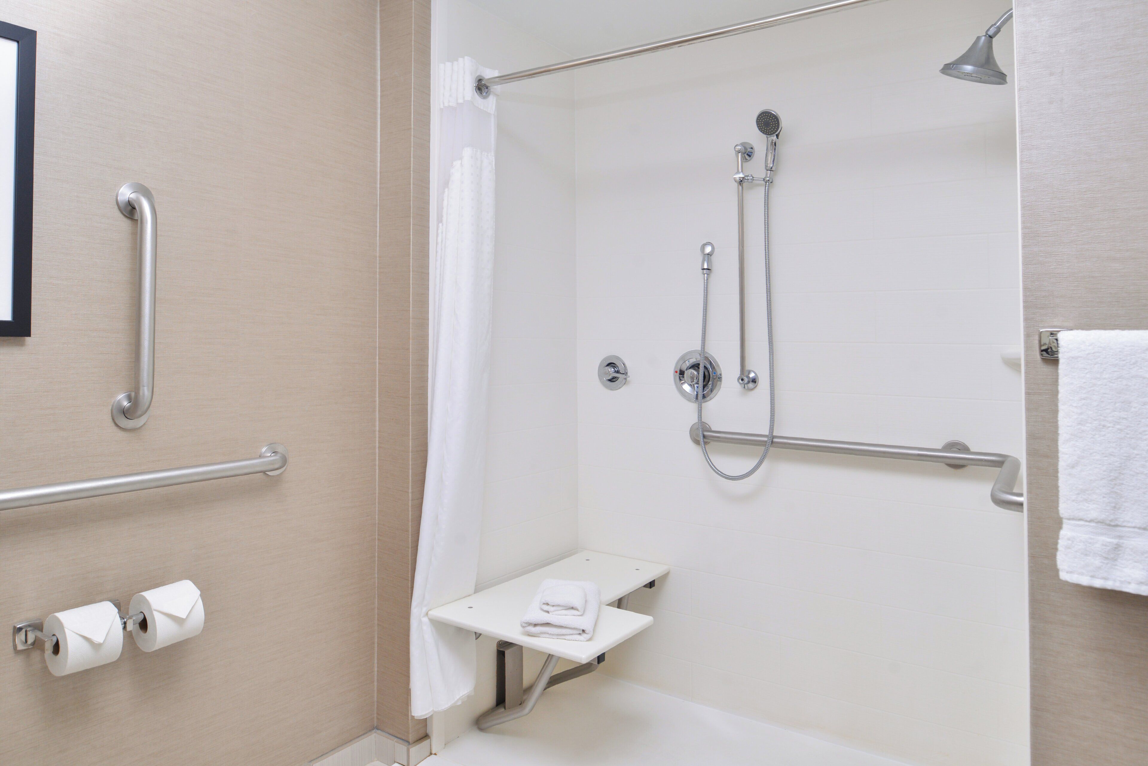 A bathroom with a shower, toilet, and a towel rack.