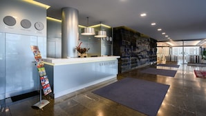 A reception area with a modern design, featuring a reception desk, clocks, and a decorative wall. - Lux Hotel (Banska Bystrica)
