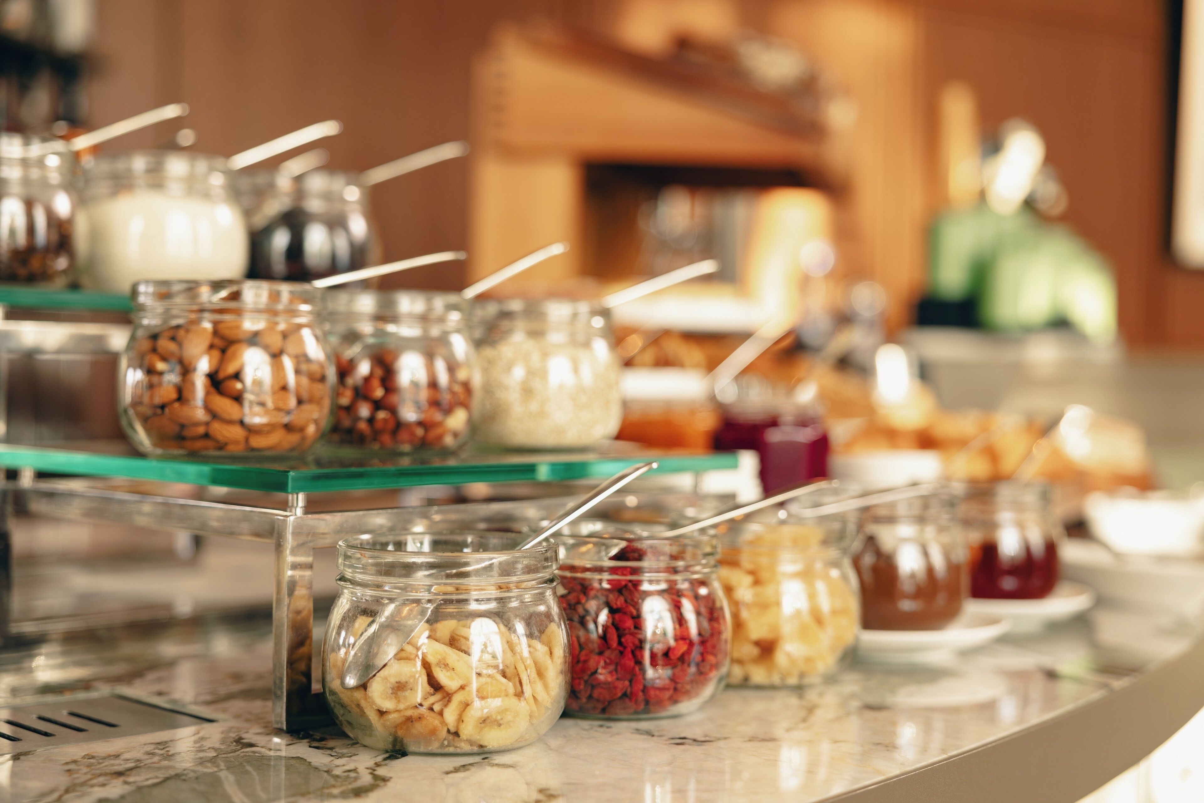 A buffet with various food items in jars, including nuts and dried fruits.