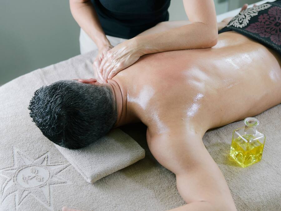 A massage therapy session in a room with a massage table, a towel, and a bottle of oil.