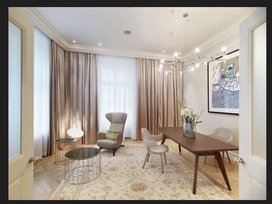 A spacious dining area with a wooden table, two chairs, a round coffee table, and a chandelier.